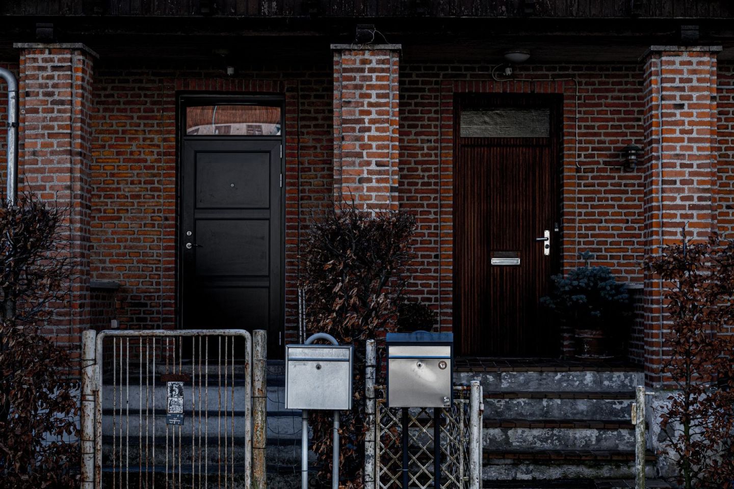 Zwei Hauseingänge in einer Klinkerfassade mit Briefkästen und Stufen
